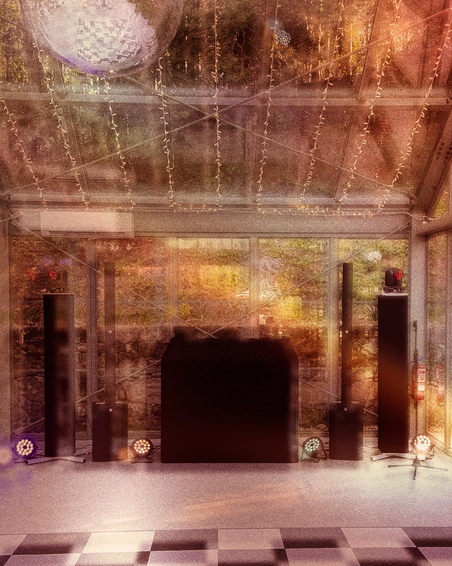 DJ booth flanked by speaker towers, uplights and a disco ball